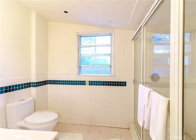 bathroom featuring lofted ceiling, toilet, tile patterned floors, a shower stall, and tile walls