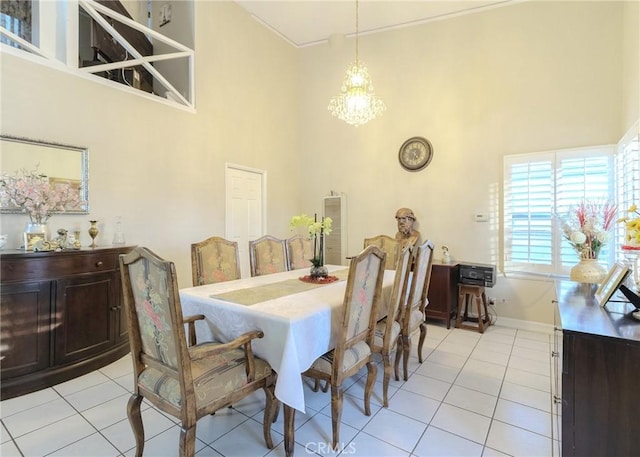 dining area featuring baseboards, a towering ceiling, an inviting chandelier, and light tile patterned floors