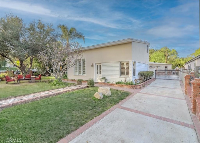 view of front of house featuring a gate, fence, a front lawn, and stucco siding