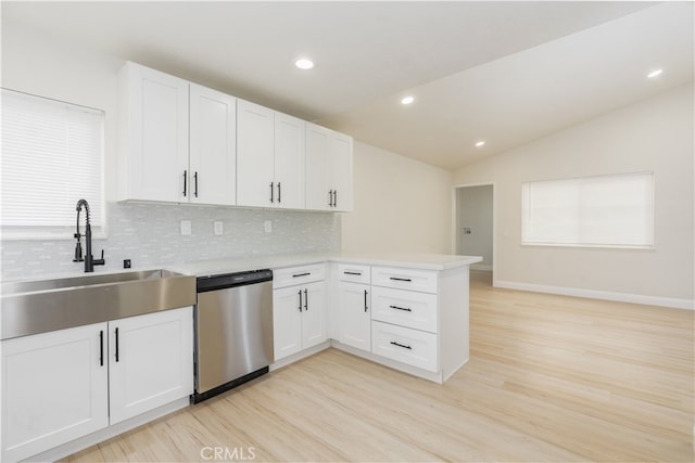 kitchen featuring white cabinetry, lofted ceiling, sink, stainless steel dishwasher, and kitchen peninsula