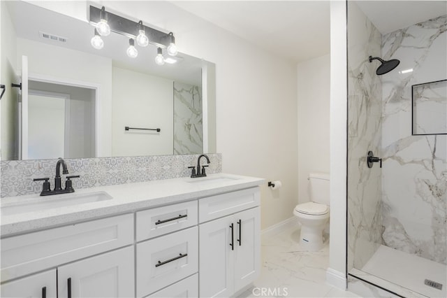 bathroom featuring vanity, a tile shower, decorative backsplash, and toilet