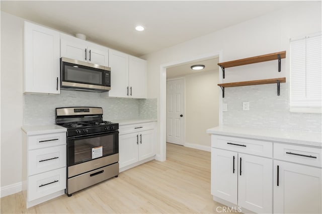 kitchen featuring backsplash, stainless steel appliances, light hardwood / wood-style floors, and white cabinets