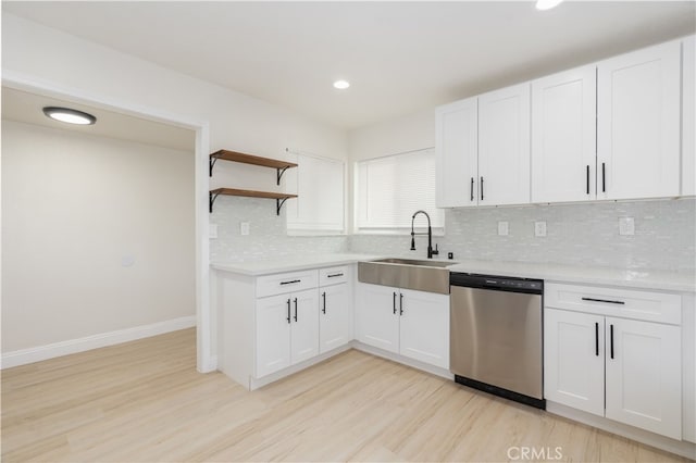 kitchen featuring sink, white cabinetry, light hardwood / wood-style flooring, stainless steel dishwasher, and decorative backsplash