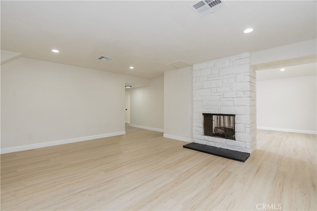 unfurnished living room featuring a stone fireplace and light hardwood / wood-style flooring