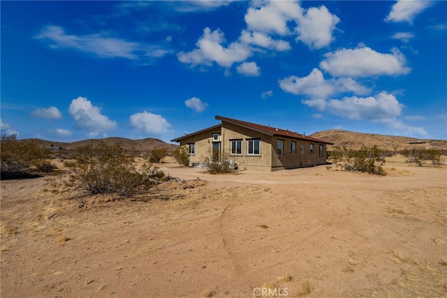 60785 La Brisa Dr, Joshua Tree, CA 92252 - rear view of property featuring stucco siding and a mountain view