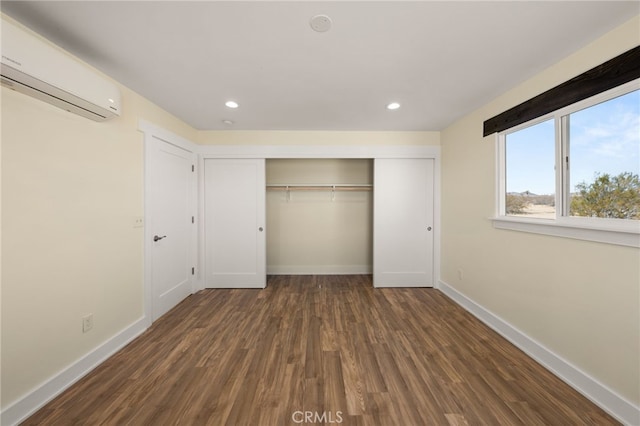 unfurnished bedroom with dark hardwood / wood-style flooring, a wall mounted air conditioner, and a closet