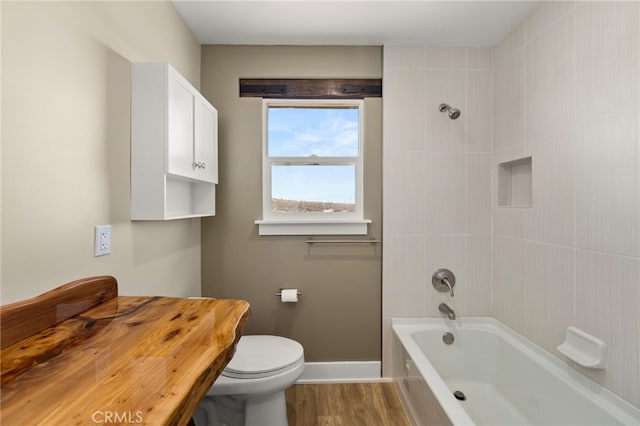 bathroom featuring tiled shower / bath, hardwood / wood-style floors, and toilet