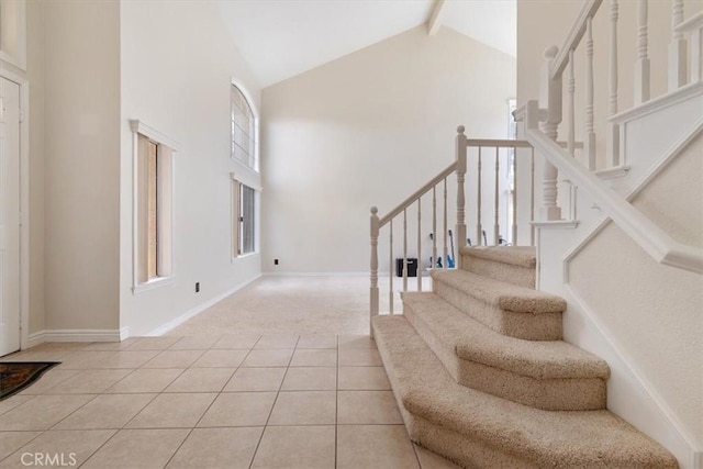 foyer featuring a healthy amount of sunlight, light tile patterned floors, high vaulted ceiling, and beamed ceiling