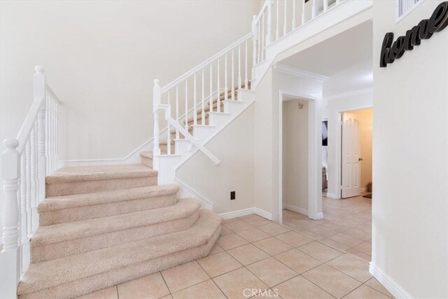 staircase with crown molding and tile patterned flooring