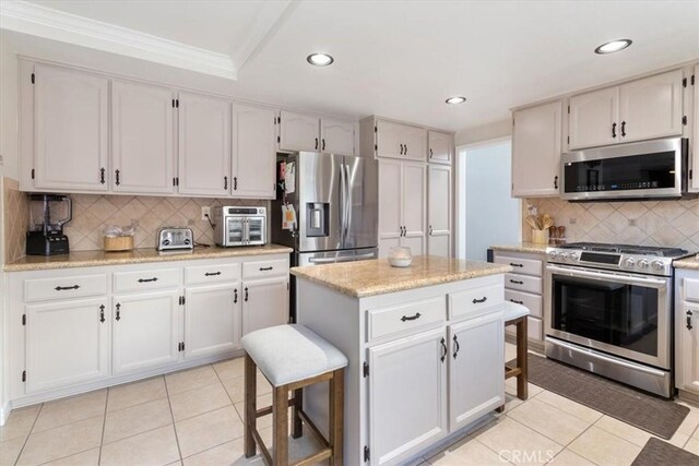 kitchen with appliances with stainless steel finishes, a kitchen island, and white cabinets