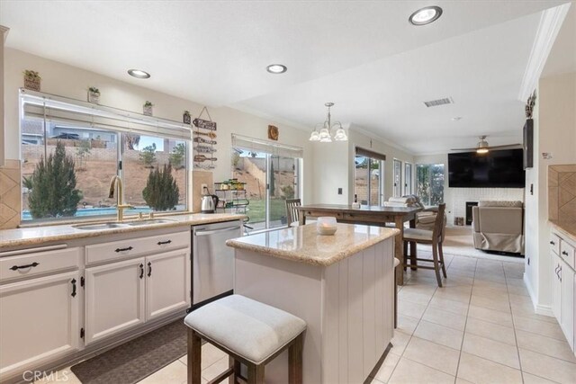 kitchen featuring white cabinetry, stainless steel dishwasher, light stone countertops, and hanging light fixtures