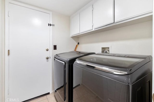 clothes washing area featuring cabinets, light tile patterned floors, and independent washer and dryer