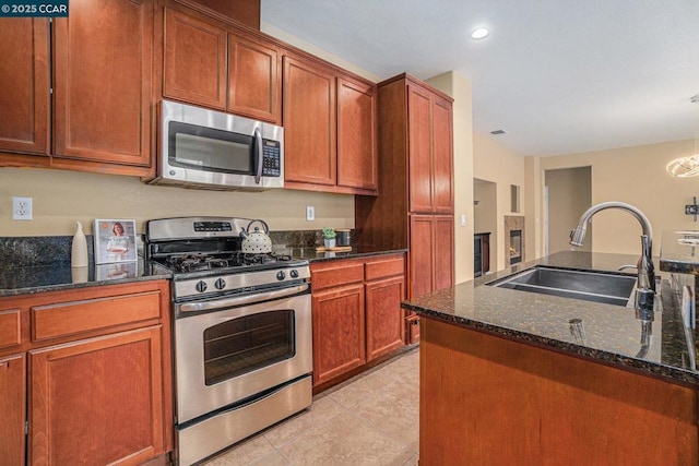 kitchen with dark stone countertops, sink, light tile patterned floors, and appliances with stainless steel finishes