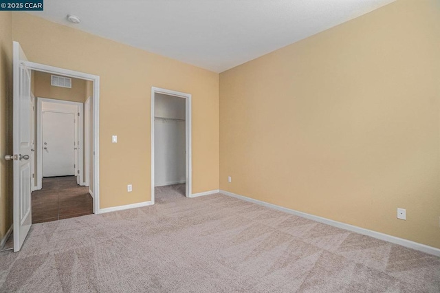 unfurnished bedroom with light colored carpet and a closet