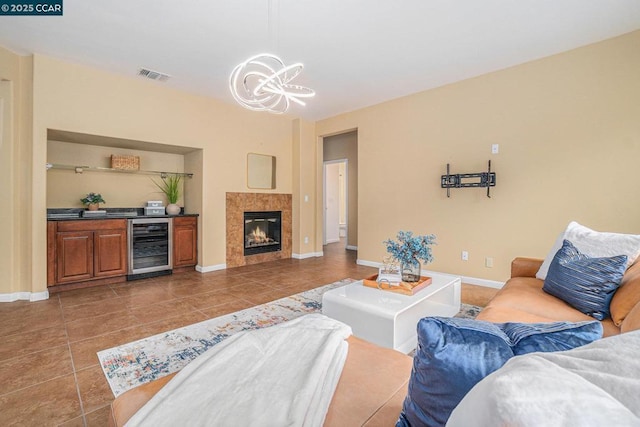 living room featuring a notable chandelier, beverage cooler, a fireplace, and dark tile patterned flooring