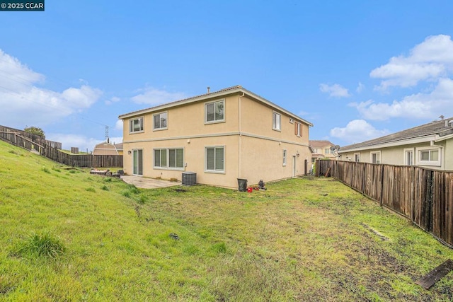 rear view of house featuring cooling unit, a patio area, and a lawn