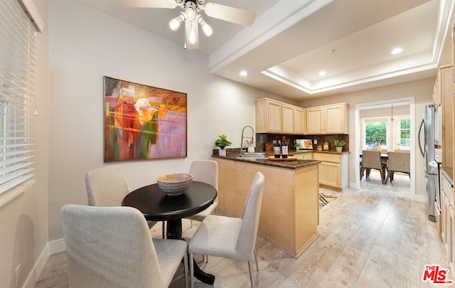 kitchen with sink, tasteful backsplash, a tray ceiling, light hardwood / wood-style floors, and kitchen peninsula