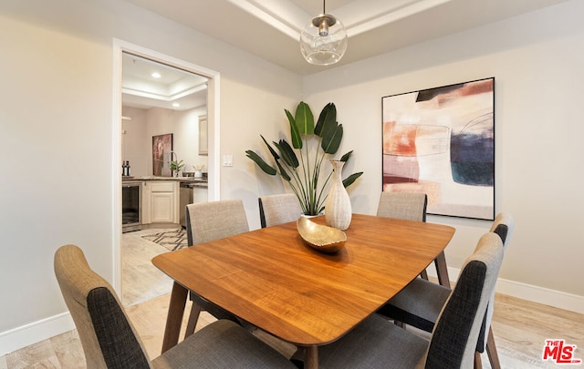 dining room featuring light hardwood / wood-style flooring, beverage cooler, and a raised ceiling