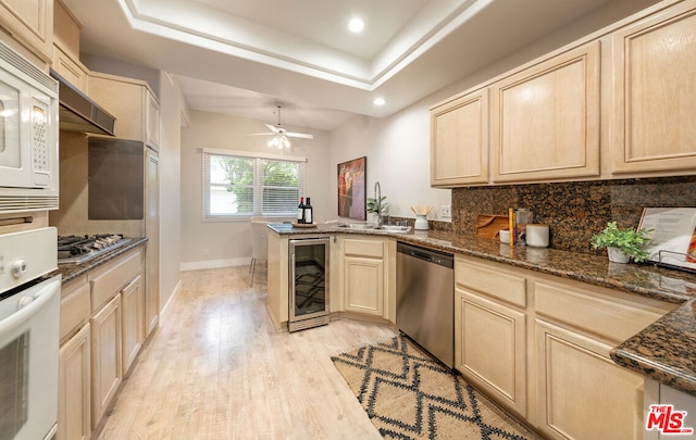 kitchen featuring wine cooler, sink, kitchen peninsula, a raised ceiling, and stainless steel appliances