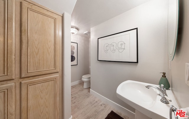 bathroom with sink, wood-type flooring, and toilet