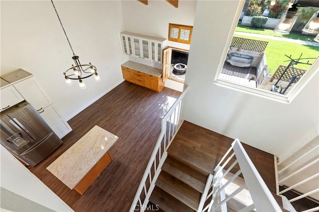 stairway with an inviting chandelier and wood-type flooring