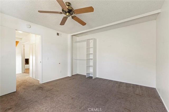 unfurnished bedroom with a textured ceiling and dark carpet