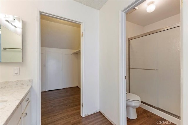 bathroom with toilet, a shower with door, vanity, and wood-type flooring