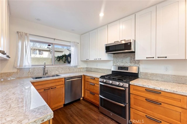 kitchen featuring appliances with stainless steel finishes, sink, light stone counters, and white cabinets