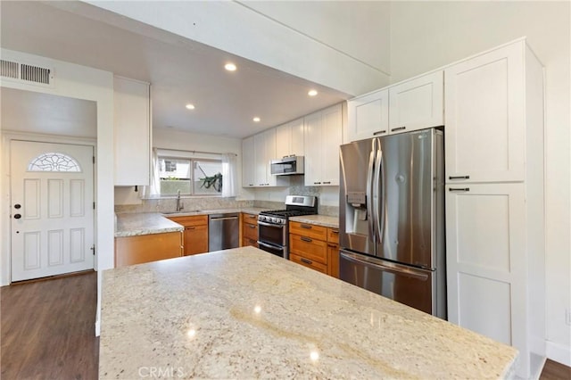 kitchen featuring appliances with stainless steel finishes, light stone countertops, white cabinets, dark hardwood / wood-style flooring, and sink