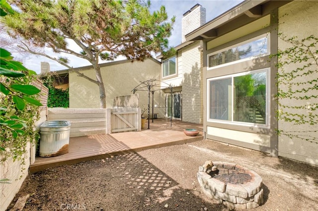 rear view of house featuring a wooden deck and an outdoor fire pit