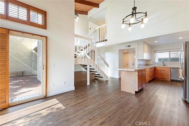 kitchen with kitchen peninsula, dark hardwood / wood-style flooring, dishwasher, beamed ceiling, and pendant lighting