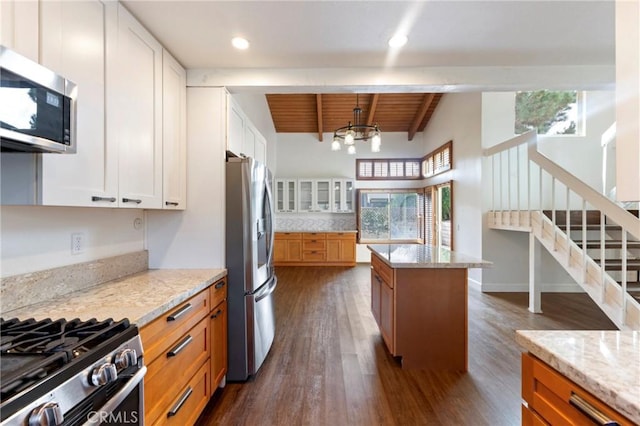 kitchen featuring appliances with stainless steel finishes, white cabinetry, light stone countertops, and a wealth of natural light