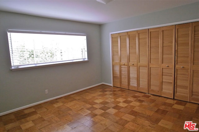 unfurnished bedroom featuring parquet flooring and a closet