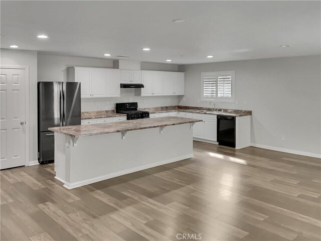 kitchen featuring white cabinetry, light wood-type flooring, black appliances, and a kitchen island