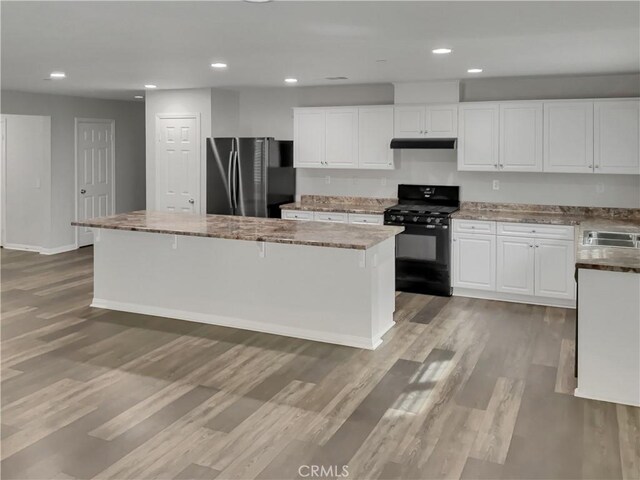 kitchen with a kitchen island, refrigerator, white cabinets, light hardwood / wood-style floors, and black gas range