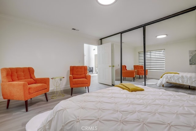 bedroom with crown molding, light hardwood / wood-style floors, and a closet