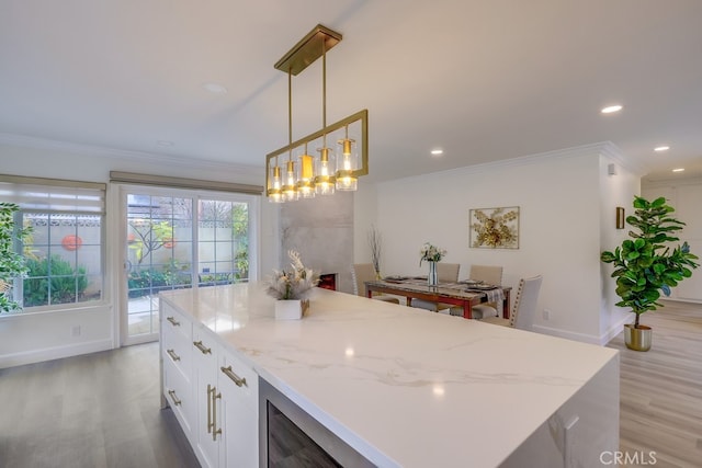 kitchen featuring hanging light fixtures, ornamental molding, white cabinets, and light hardwood / wood-style flooring