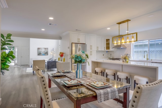 dining space with crown molding, sink, and light wood-type flooring