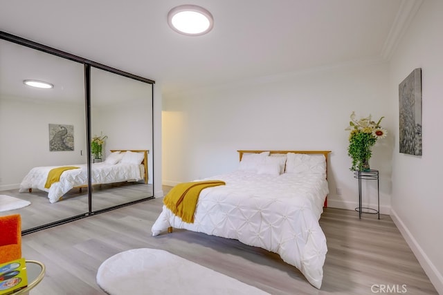 bedroom featuring wood-type flooring, ornamental molding, and a closet