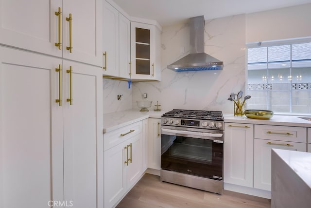 kitchen with white cabinetry, decorative backsplash, stainless steel gas range oven, and wall chimney exhaust hood