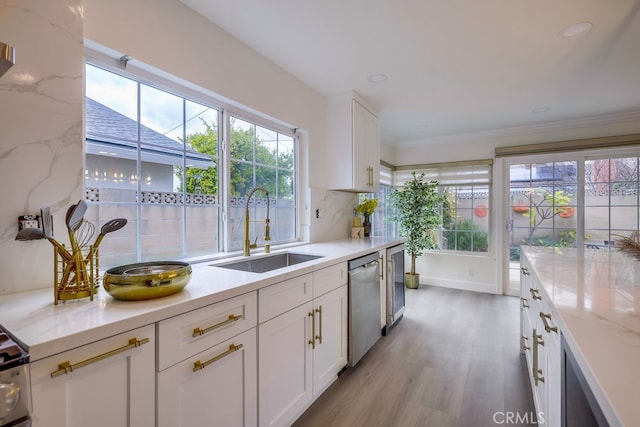 kitchen featuring light stone counters, sink, stainless steel dishwasher, and white cabinets