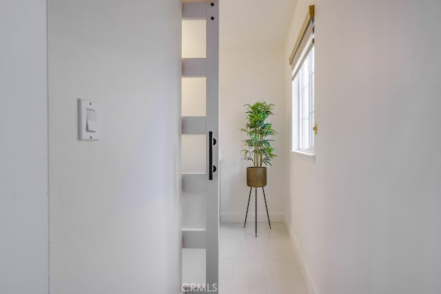 corridor with light tile patterned floors and a barn door