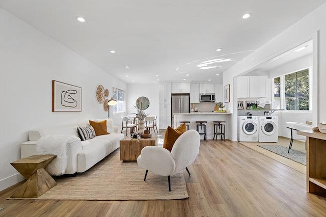 living room with independent washer and dryer and light hardwood / wood-style floors