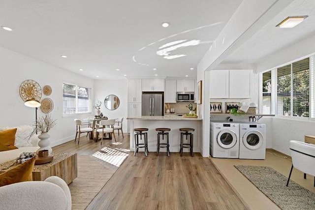 washroom with washer and clothes dryer and light hardwood / wood-style flooring