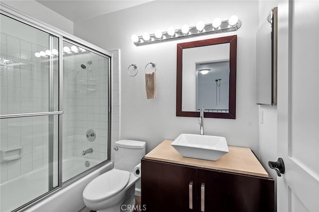 full bathroom featuring vanity, bath / shower combo with glass door, and toilet