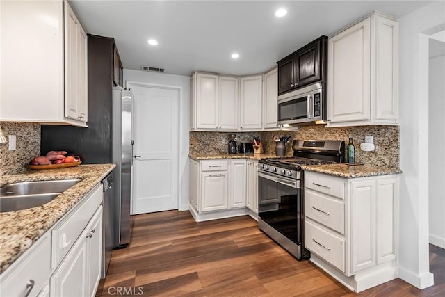 kitchen featuring white cabinetry, appliances with stainless steel finishes, dark hardwood / wood-style floors, and light stone counters