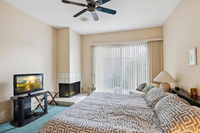 carpeted bedroom with ceiling fan and a fireplace