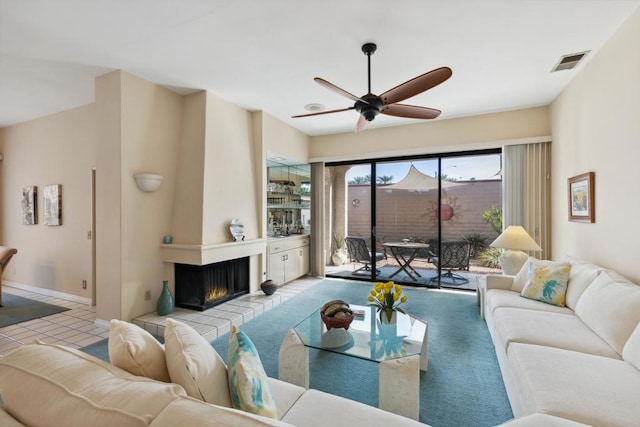 carpeted living room featuring a fireplace and ceiling fan