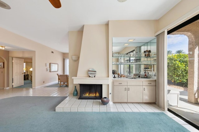 bar featuring sink, light colored carpet, a tile fireplace, and ceiling fan