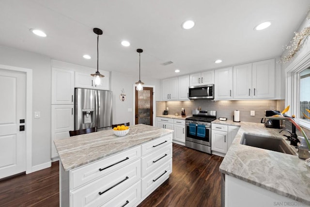 kitchen featuring sink, a center island, hanging light fixtures, stainless steel appliances, and white cabinets